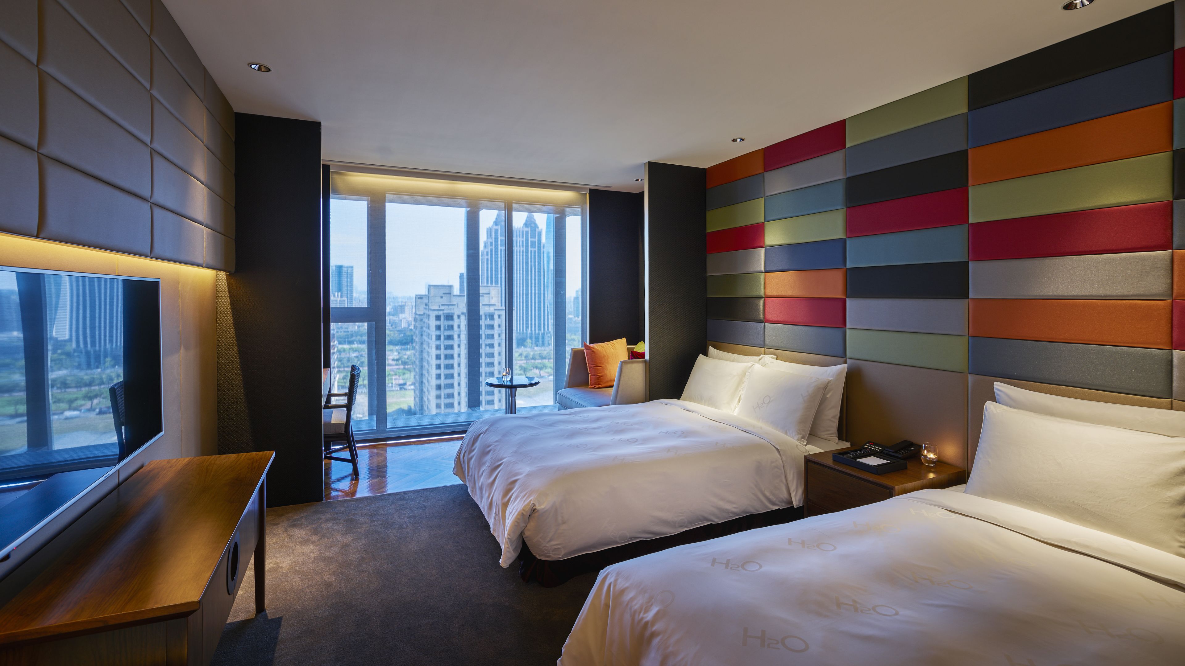 Une chambre d’hôtel moderne avec deux lits, une télévision et une vue sur la ville.