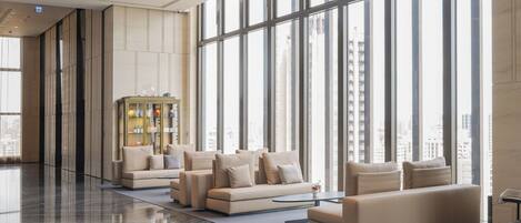 A spacious lobby with a high ceiling, large windows, and a modern sofa arrangement.
