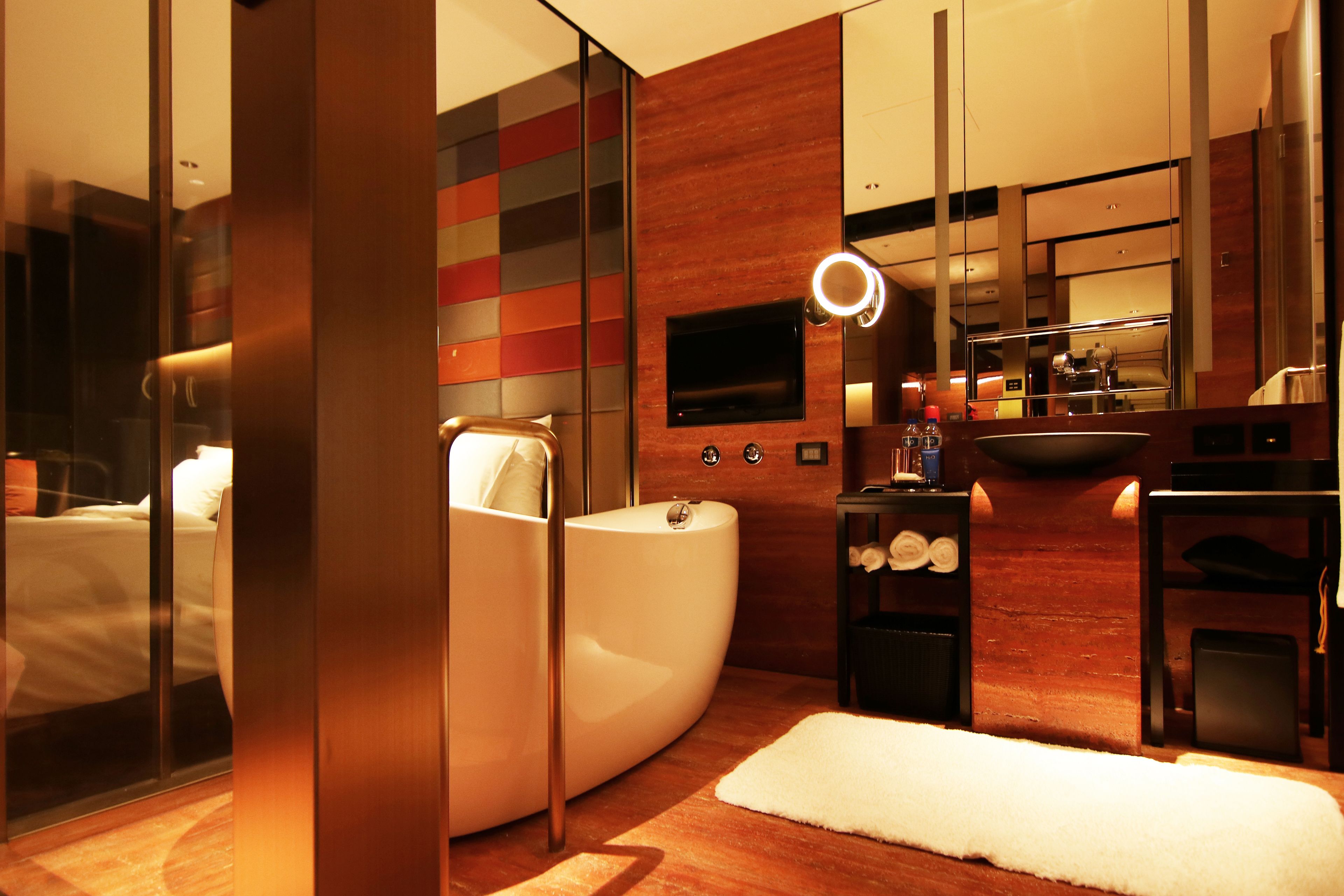 Un baño moderno con bañera, un espejo grande y un televisor.