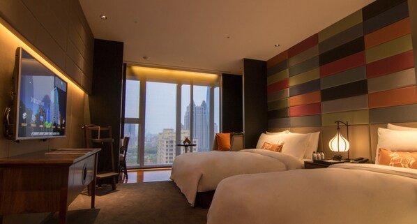 A hotel room with two beds, a TV, a desk, and a large window with a city view. - H2O Hotel (Kaohsiung)