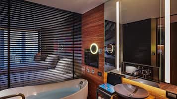 A modern bathroom with a freestanding bathtub, a vanity with a large mirror, and a wooden accent wall.