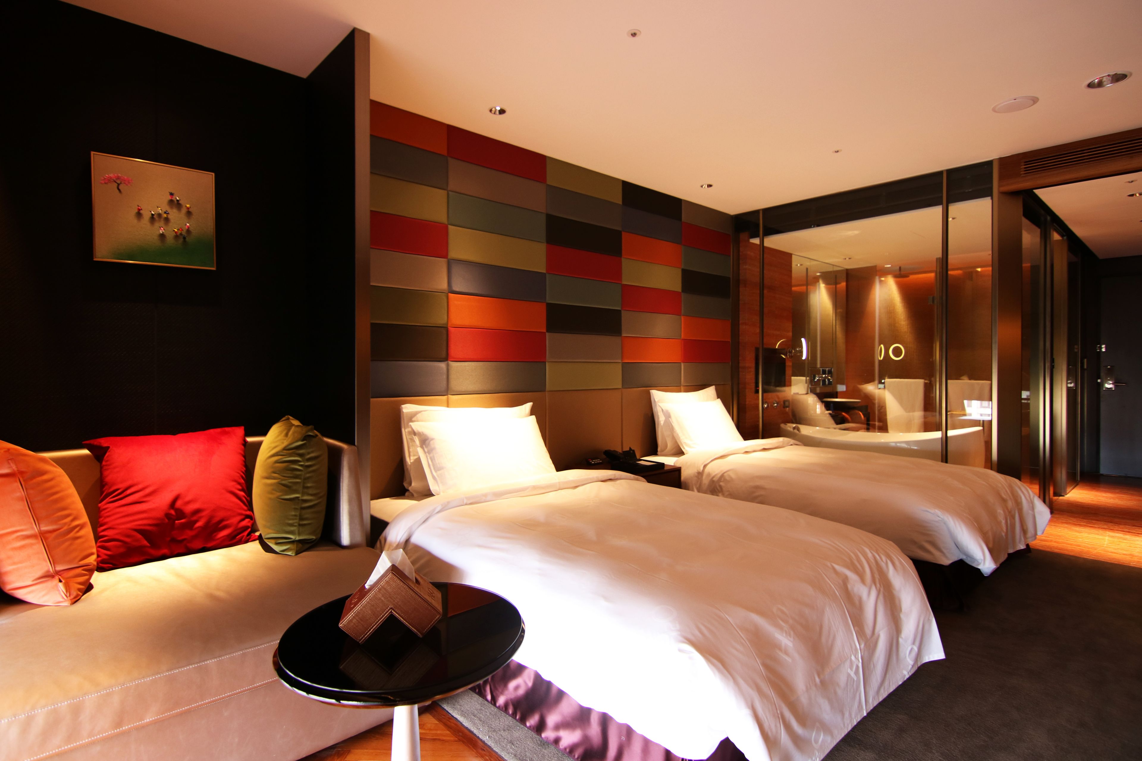A hotel room with two beds, a sofa, a small table, and a colorful wall.