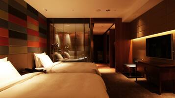 A hotel room with two beds, a TV, and a desk.
