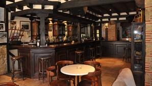 Un espace bar avec des poutres en bois, des tabourets de bar et une table ronde.