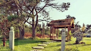 A stone pathway leading to a wooden gazebo surrounded by trees. - Jake & Jo's Cottages (Brackley Beach)