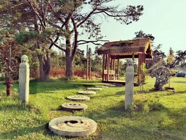 A stone pathway leading to a wooden gazebo surrounded by trees.