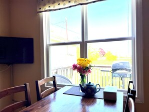 A wooden dining table with a teapot and a vase of flowers. - Jake & Jo's Cottages (Brackley Beach)