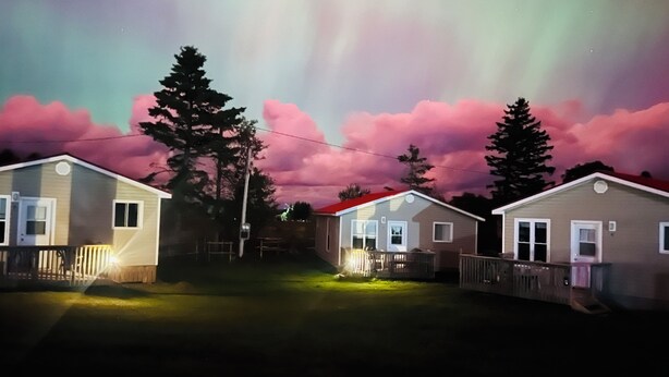 A row of single-story mobile homes with a clear night sky and visible aurora borealis. - Jake & Jo's Cottages (Brackley Beach)