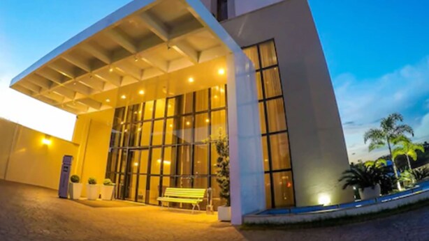 Un edificio moderno con una amplia entrada de vidrio y un área de espera cubierta.