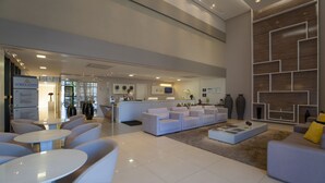 Un moderno vestíbulo de hotel con mostrador de recepción, zona de estar y una gran pared con estanterías geométricas.