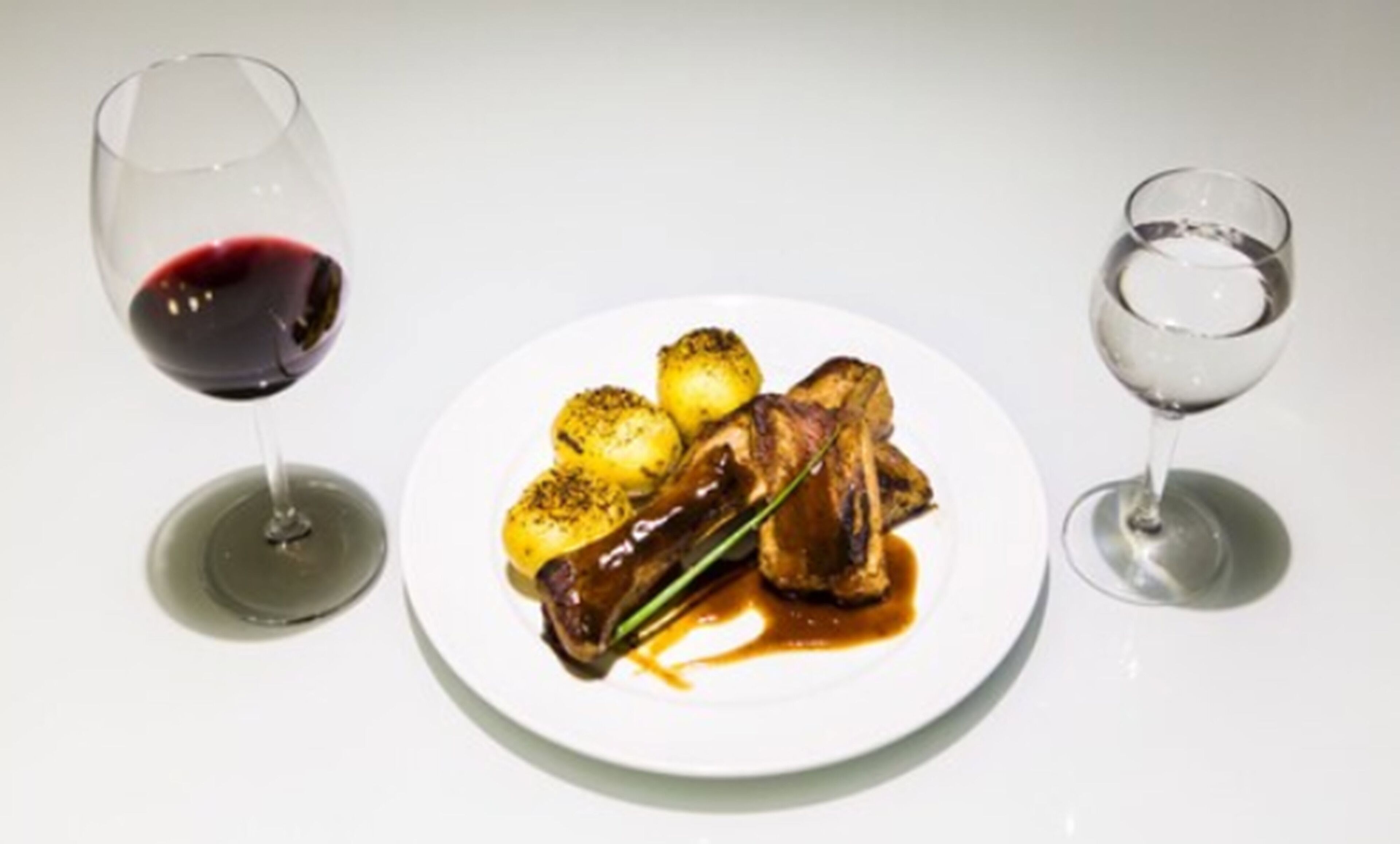Un plato de comida con una copa de vino tinto y una copa de vino blanco.