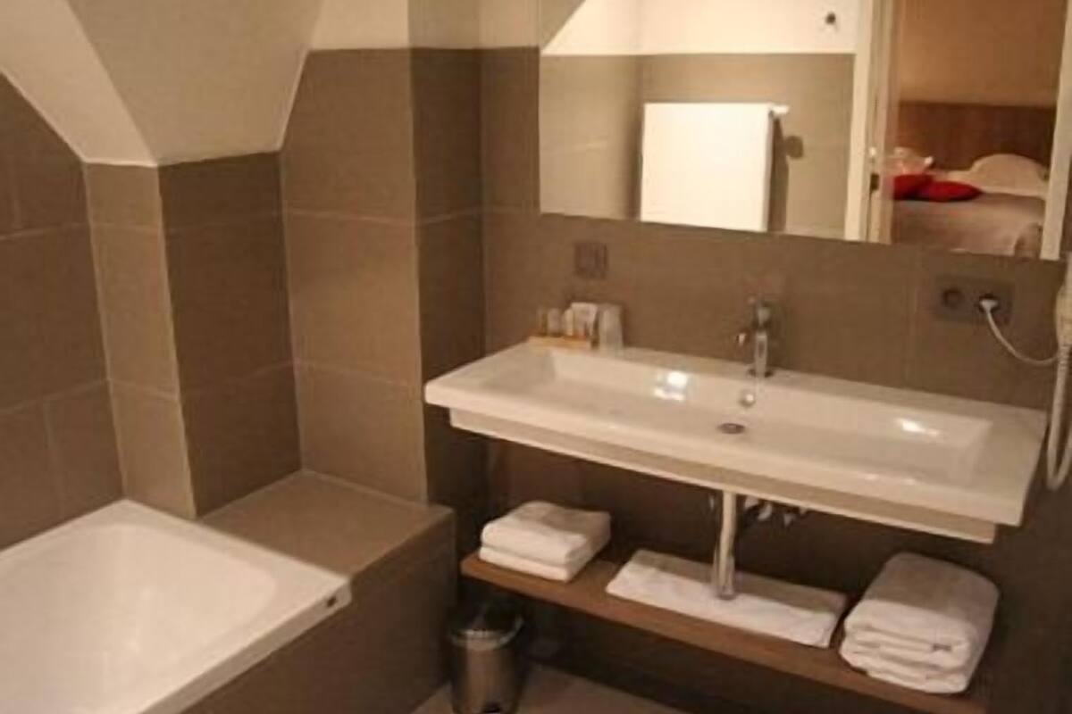 Une salle de bain moderne avec un grand lavabo, un miroir et une baignoire.