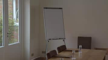 A conference room with a whiteboard, a long table, and four chairs.
