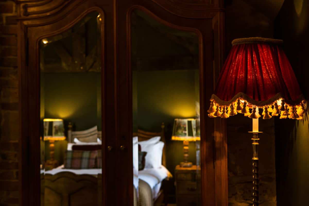 Une chambre avec un lit, une table de chevet et une lampe dotée d’un abat-jour rouge.