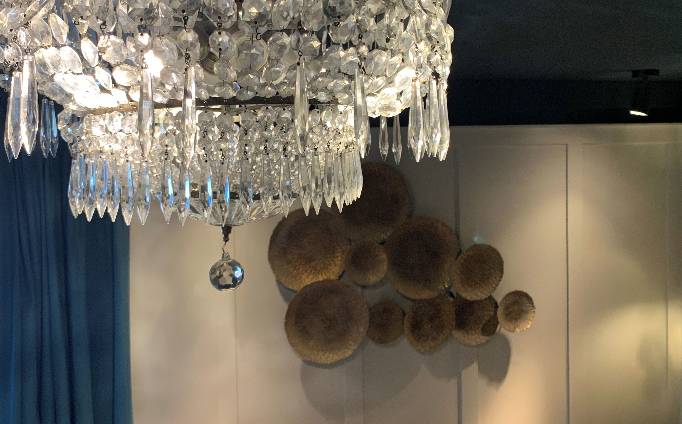 Un lustre composé de plusieurs éléments en cristal et agrémenté d’un ornement en cristal suspendu.