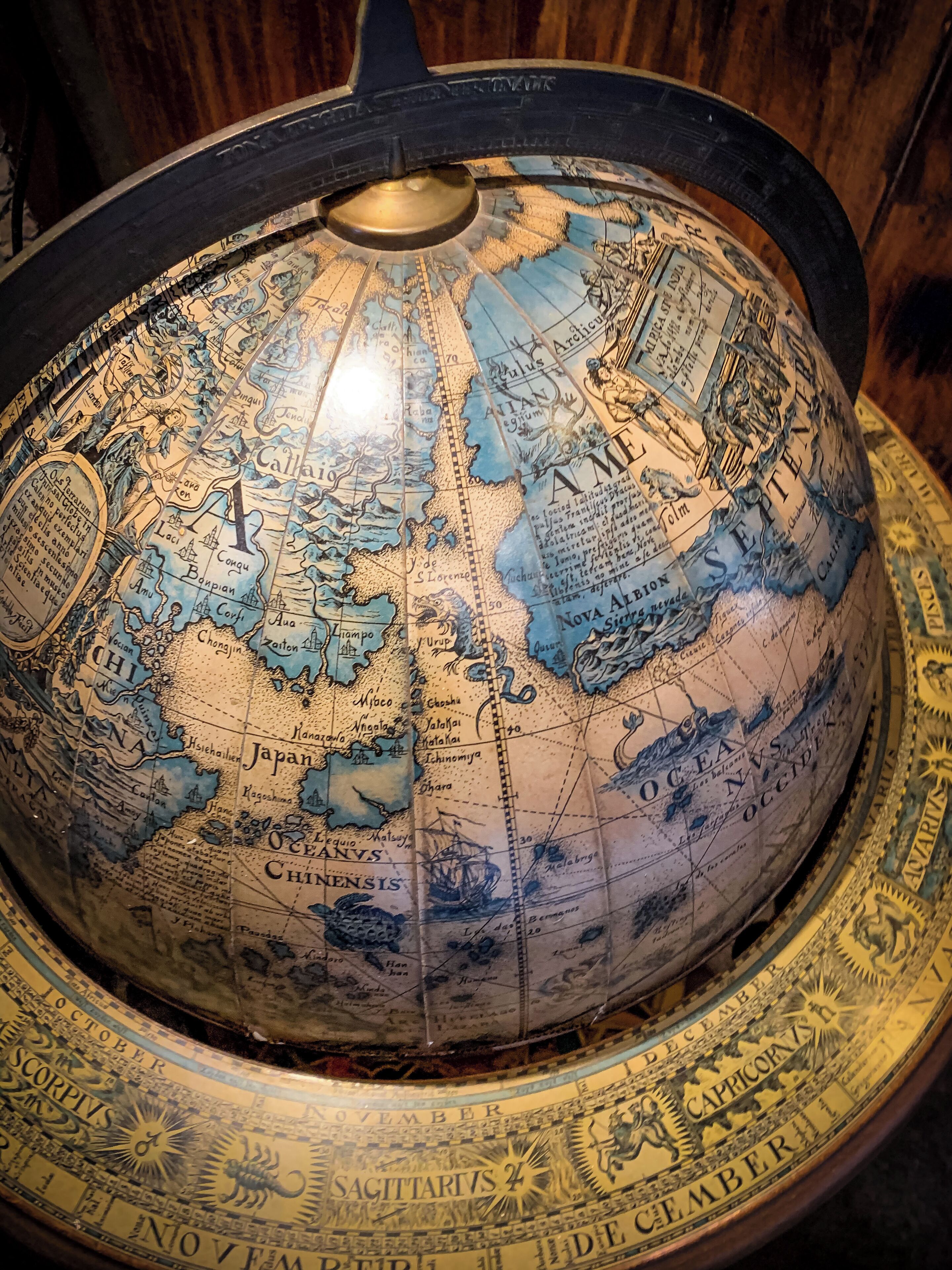 A detailed globe with a metallic stand, featuring various geographical regions and historical illustrations.