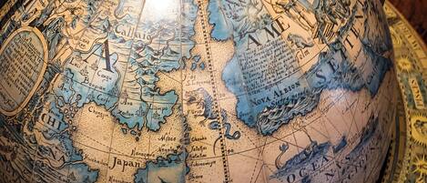 Un globe détaillé, doté d’un support métallique, représentant différentes régions géographiques et illustré d’images historiques.