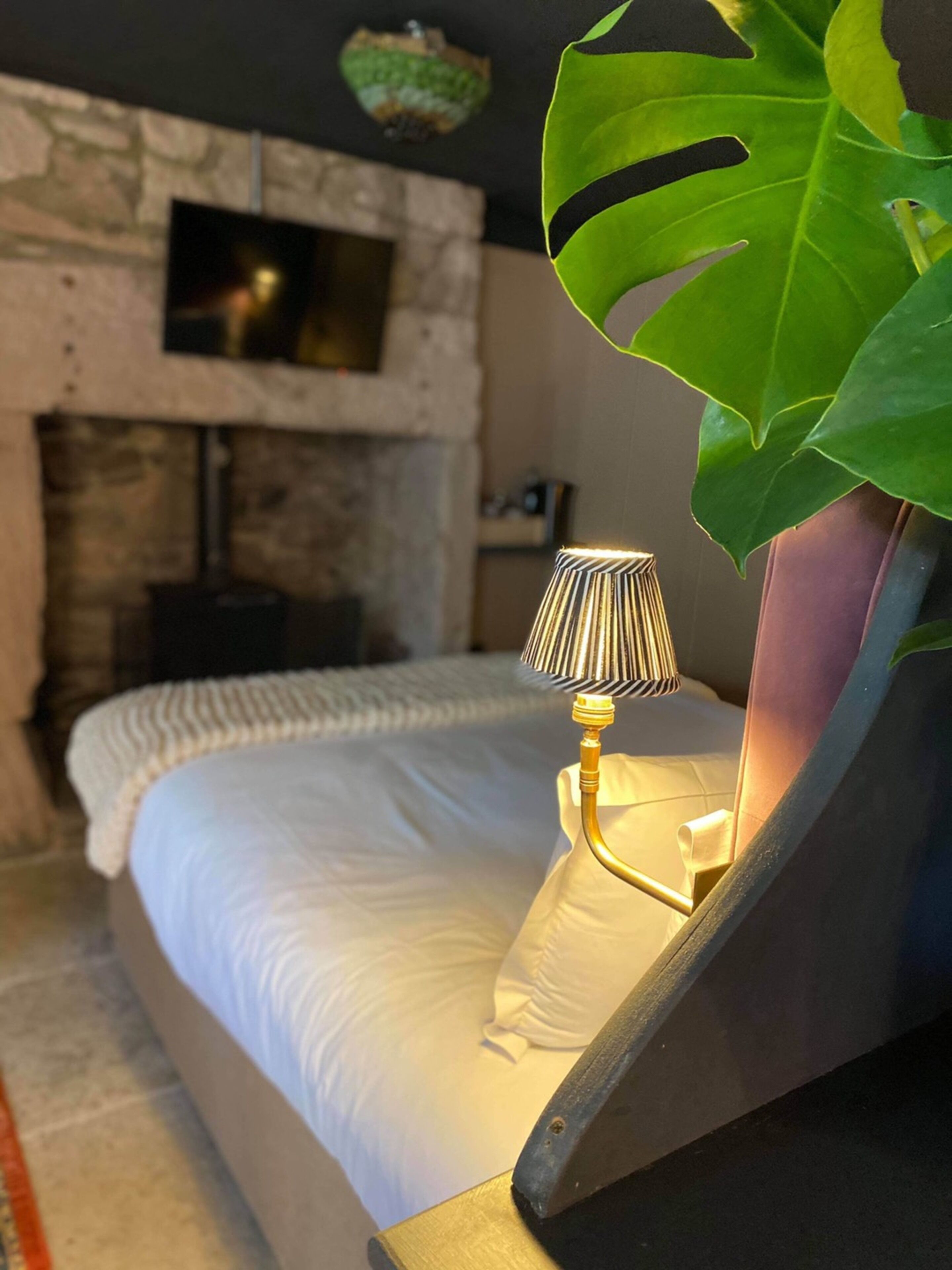 Una cama con una colcha blanca y una lámpara con pantalla a rayas.