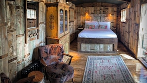 Una habitación rústica con una cama de madera, una silla y un espejo grande.