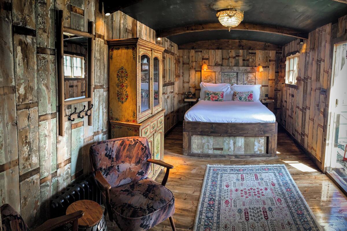 Une chambre rustique avec un lit en bois, une chaise et un grand miroir.