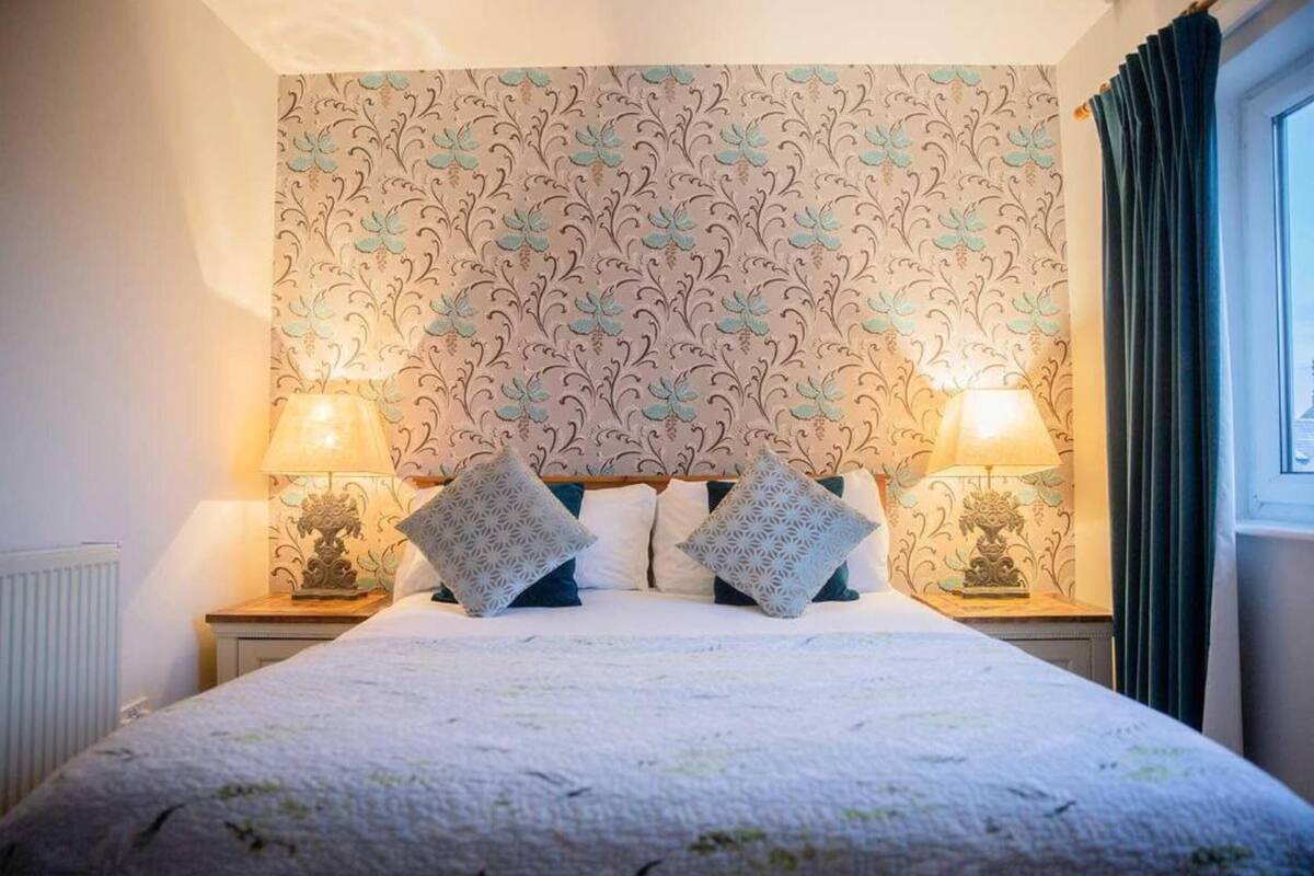 Un lit bien fait, agrémenté d’oreillers à motifs et de deux lampes de chevet.