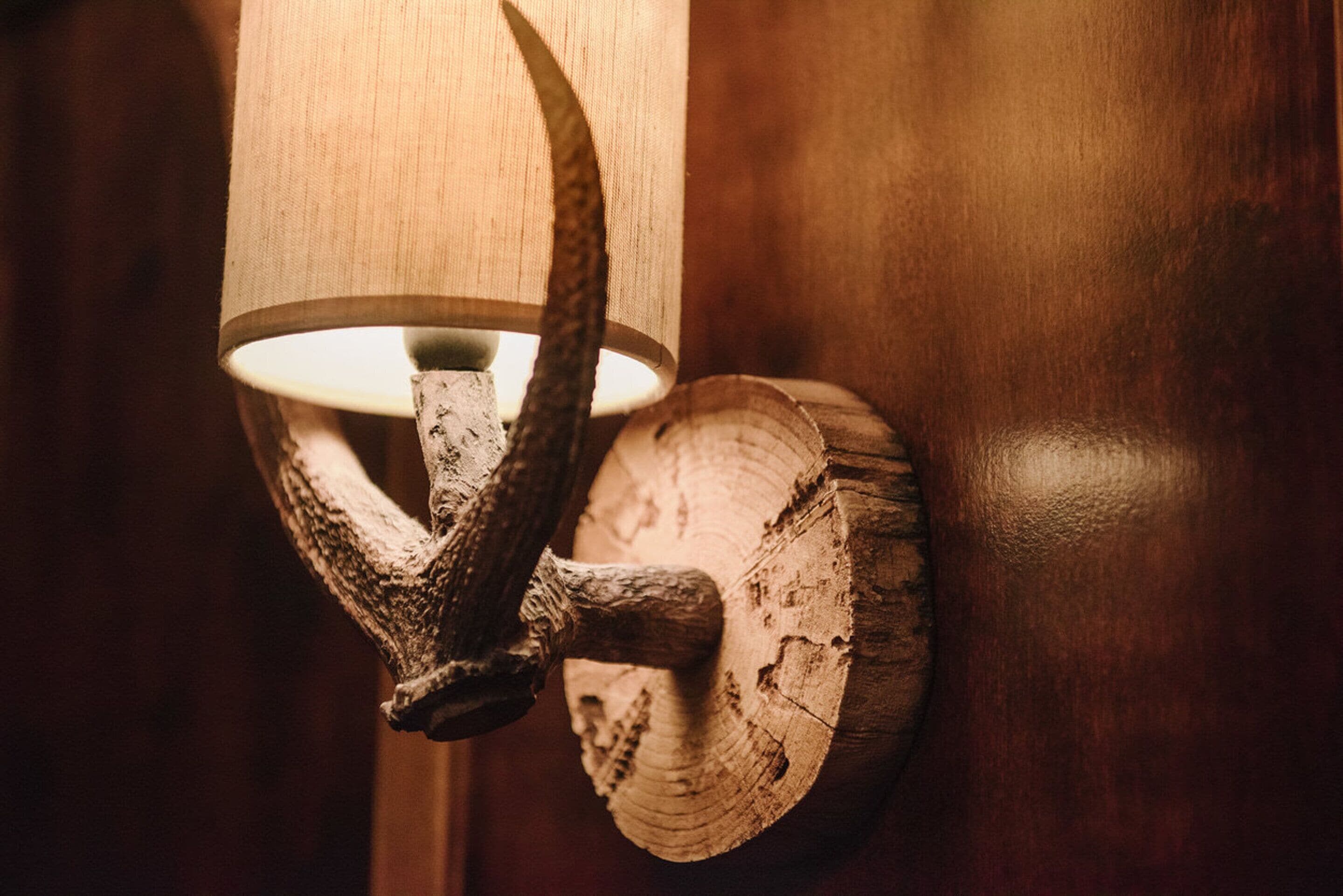 Una lámpara de pared de estilo rústico con adornos de astas y una base de madera.