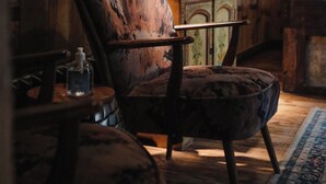 Una habitación rústica con un armario de madera, un sillón acolchado y una alfombra estampada.