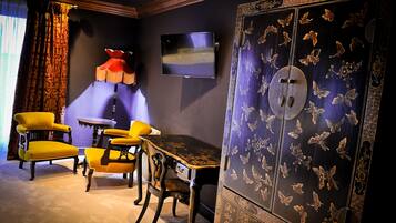 A room with a TV mounted on the wall, a table with chairs, and a large cabinet with butterfly designs.