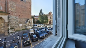 A parking lot with cars and a historic building with arched windows and a brick facade. - B&B Pergola House (Lucca)