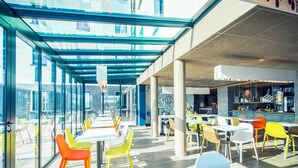 Ein moderner Essbereich mit Glaswänden, bunten Stühlen und einer Bar.