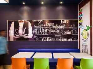 Ein Restaurantinneres mit einer großen Speisekarte, einer Sitzgruppe mit blauen Boxsitzplätzen und einem Schild, das ein Nachhaltigkeitsprogramm anzeigt.