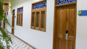 A corridor with patterned floor tiles, wooden doors, and windows with blue signage.