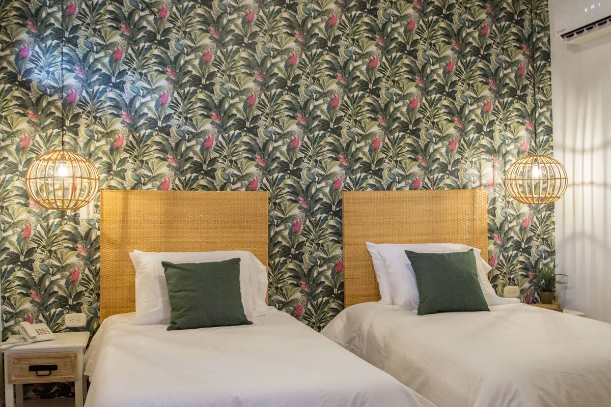 Une chambre avec deux lits, un plafond en bois et un papier peint à motifs.
