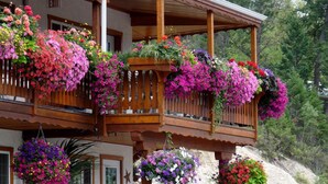 A two-story building with balconies adorned with hanging flower baskets. - Gateway Motel (Radium Hot Springs)