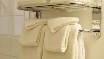 Un baño con un perchero con toallas dobladas y un rollo de papel higiénico.