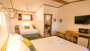 A hotel room with a large bed, a desk with a chair, a television, and a small refrigerator. - Gateway Motel (Radium Hot Springs)