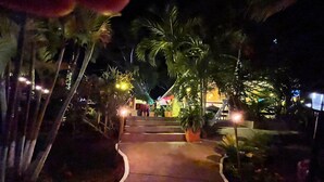 A nighttime pathway leading to a building with steps and potted plants.