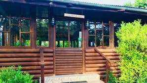 A wooden cabin with a reception sign, stone steps, and lush greenery around.