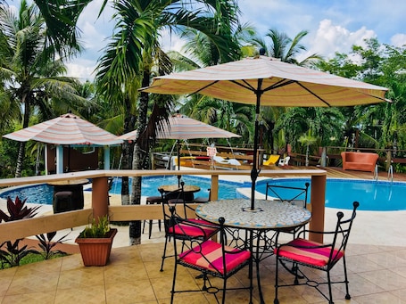 Una piscina al aire libre, sombrillas, sillones reclinables de piscina