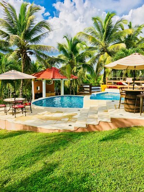 A pool area with a gazebo, lounge chairs, and palm trees.