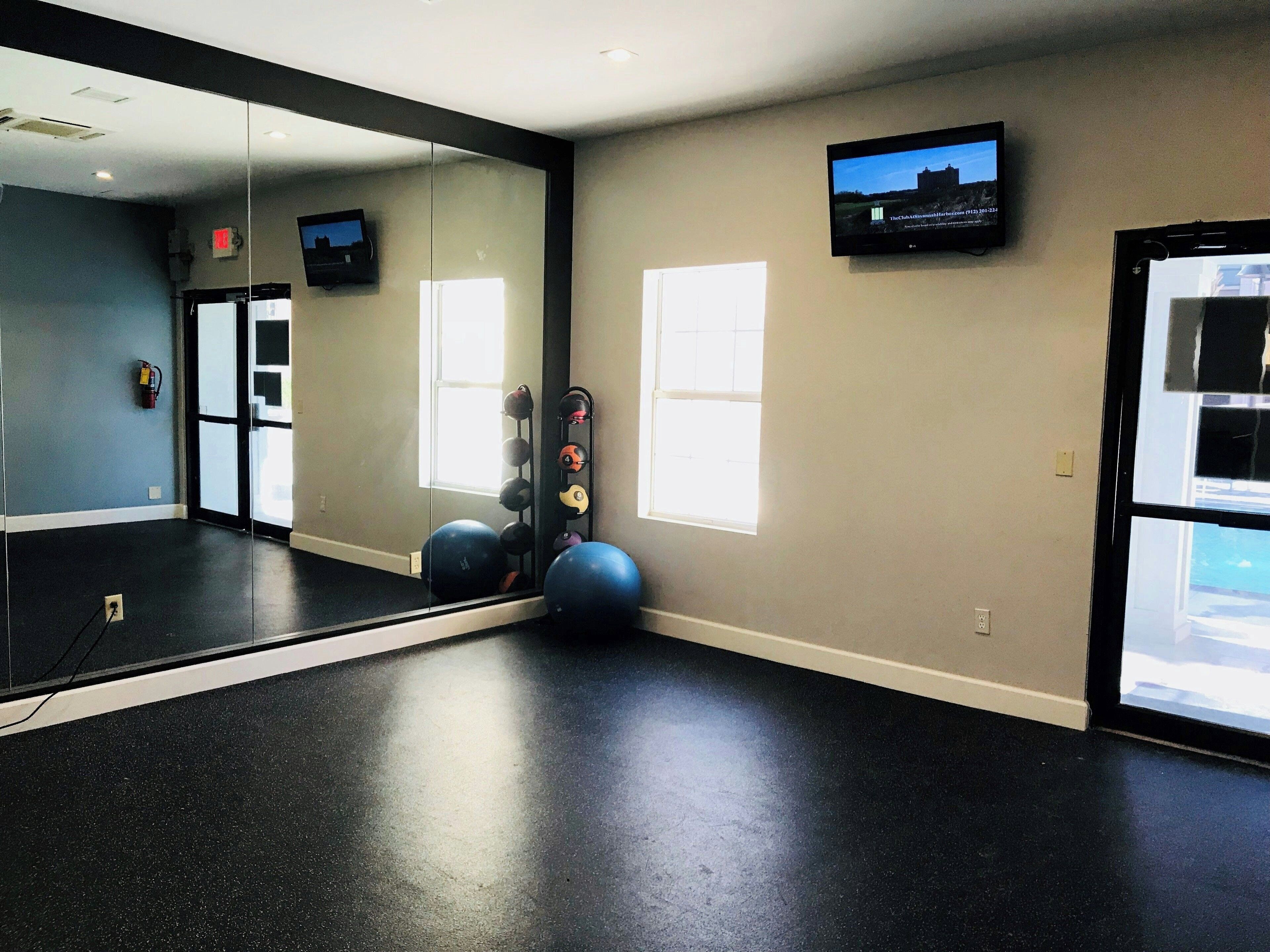Une salle de sport équipée de matériel d’exercice, dotée d’un grand miroir et d’un téléviseur fixé au mur.