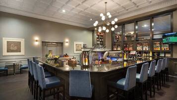 A bar area with a central bar, seating, and a television screen.
