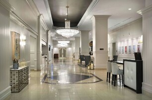Un amplio vestíbulo de hotel con una gran araña, una recepción y una zona de estar.