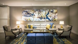 A living room with a sofa, two armchairs, a coffee table, and a rug. - The DeSoto (Savannah)