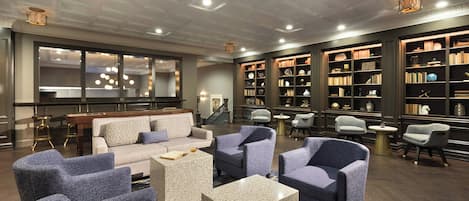 Un espace de détente moderne, doté de canapés, de fauteuils et d’une bibliothèque remplie de livres.