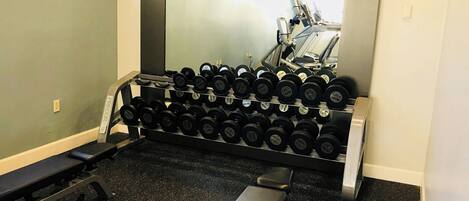 A gym with exercise equipment, including dumbbells and treadmills.