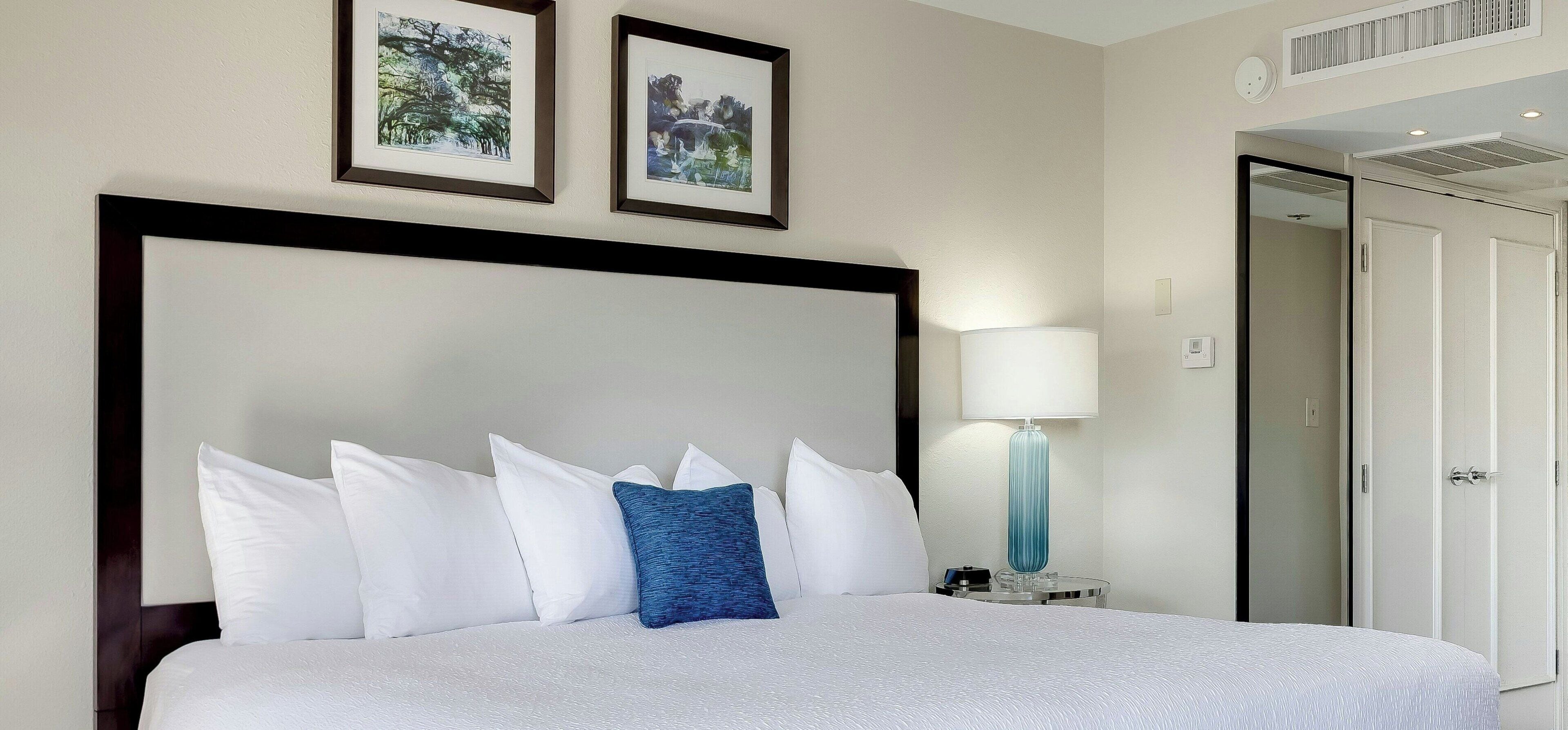 A hotel room with a large bed, a nightstand with a lamp, and two framed pictures on the wall.