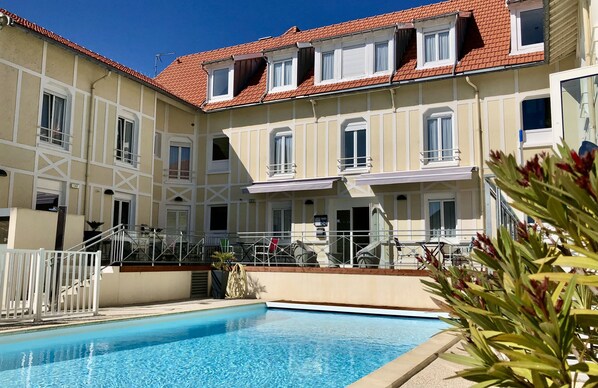 Una piscina al aire libre de temporada, sillones reclinables de piscina