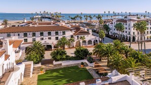 A coastal hotel with a courtyard, palm trees, and a view of the beach and ocean. - Hotel Californian (Santa Barbara)