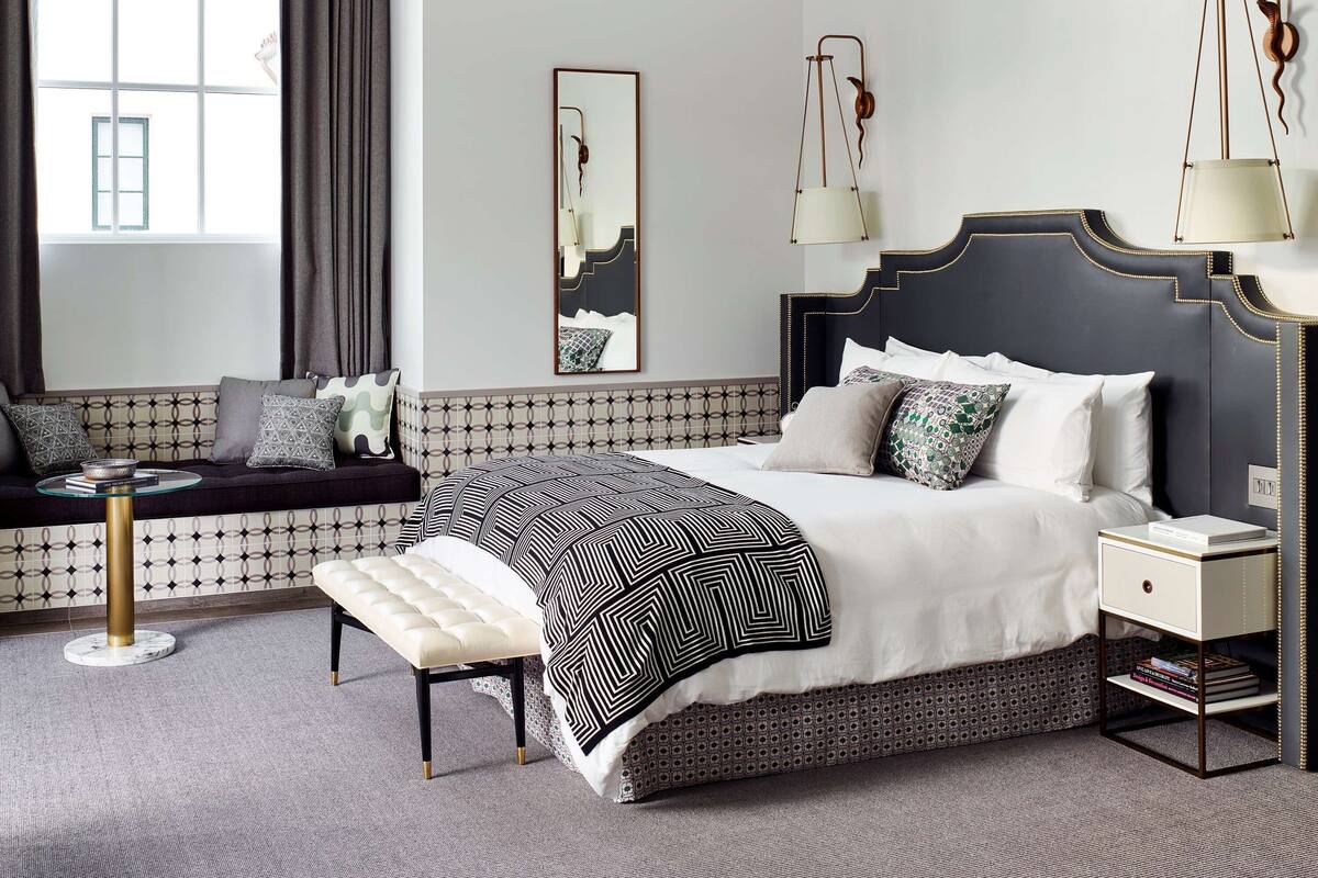 A modern bedroom with a large bed, a sofa, a small table, and a bedside lamp.